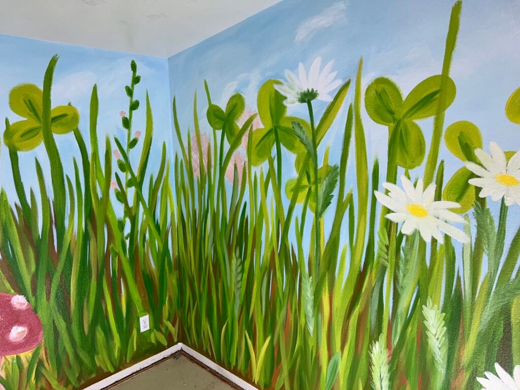 a wall with large flowers and grass painted on