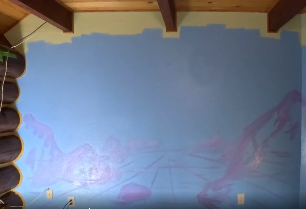Mostly blank blue wall with the start of a mural on it